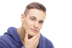 Studio shot of a young man checking the skin on his face isolated on white background